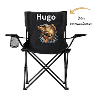 Peut inclure: Chaise de camping pliante noire avec un motif de poisson. Le dossier affiche le nom "Hugo" au-dessus d'une illustration détaillée d'un poisson doré avec des nageoires orange et des éclaboussures d'eau bleue. Comprend un porte-gobelet.