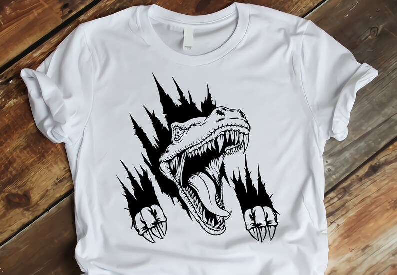 May include: A white t-shirt with a black graphic of a dinosaur head breaking through the fabric. The dinosaur has sharp teeth and claws.