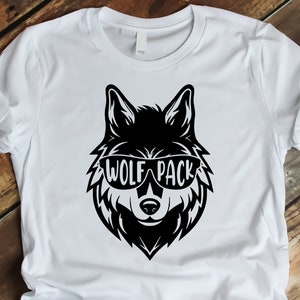 May include: White t-shirt with a black wolf wearing sunglasses and the text "Wolf Pack" printed on the front.