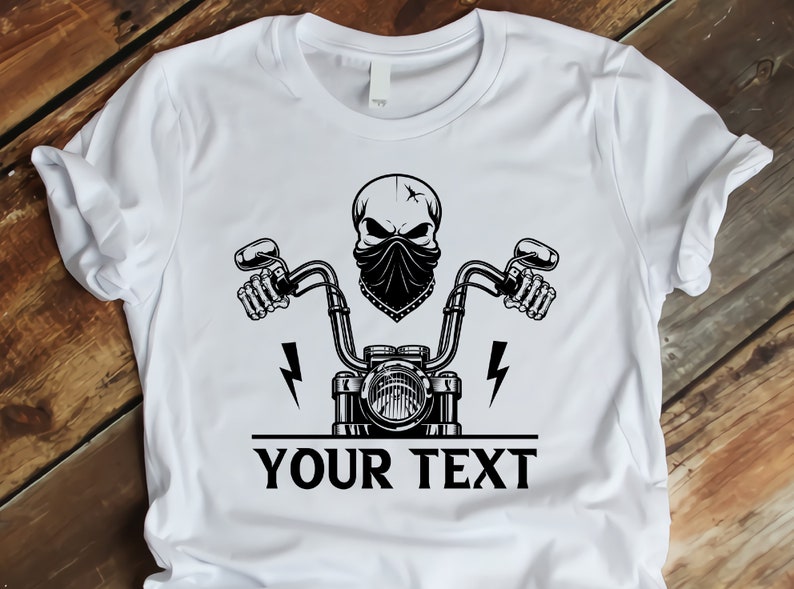 May include: White t-shirt with a black and white graphic of a skull wearing a bandana and riding a motorcycle. The text "YOUR TEXT" is printed below the graphic.