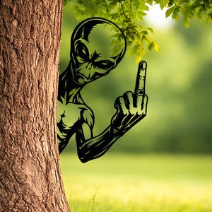 May include: A black and green alien figure peeking from behind a tree, extending a hand with the middle finger raised. The background is a blurred green field and foliage.