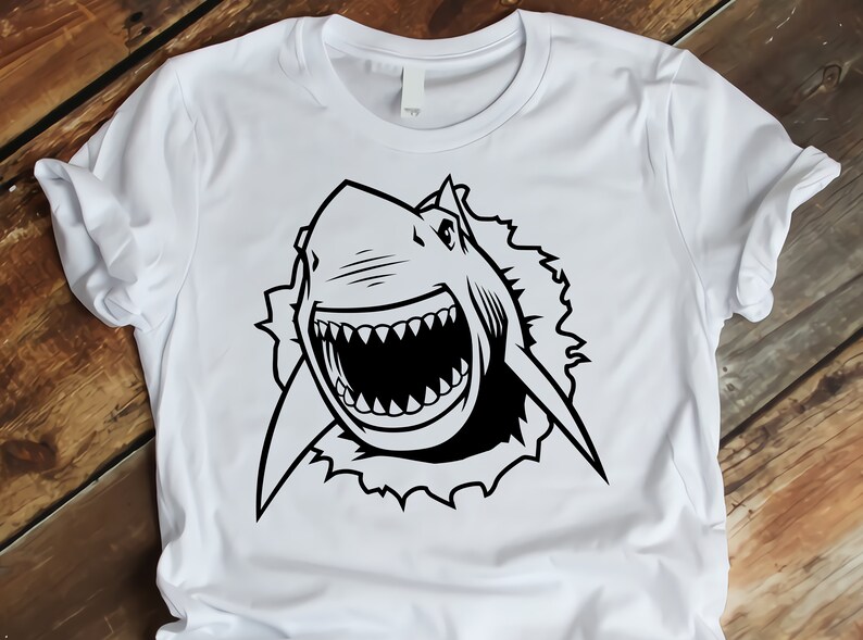 May include: A white t-shirt with a black and white graphic of a shark's head breaking through a wall.