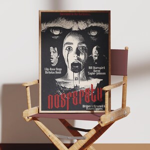 May include: A movie poster for the film "Nosferatu" with a black background and red text. The poster features a close-up of a woman's face with blood dripping from her mouth. The text on the poster reads "Succumb to the Darkness" and lists the actors Lily-Rose Depp, Nicholas Hoult, Bill Skarsgård, Aaron Taylor-Johnson, and the director Robert Eggers.