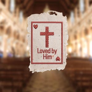 Op de afbeelding: Geborduurde kaart met een rood kruis, harten en de tekst "Loved by Him". De kaart heeft een gescheurde, getextureerde rand en een rechthoekige rand. De achtergrond is een wazige afbeelding van een kerkinterieur.