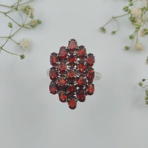 Könnte beinhalten: Ein silberner Ring mit einem Cluster aus roten Edelsteinen in sechseckiger Form.