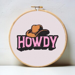 Könnte beinhalten: Kreuzstichmuster mit einem braunen Cowboyhut und dem Wort "HOWDY" in rosa Buchstaben.