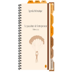 May include: A tan and brown spiral bound notebook with the title "Le parachute de l'entrepreneur" and the text "Edition 2022". The cover features a silhouette of a person skydiving with a parachute.