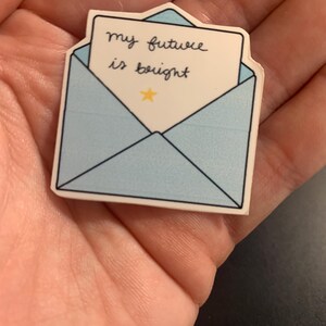 May include: A light blue sticker in the shape of an envelope with the words "my future is bright" written on a white paper. A small yellow star is below the text.