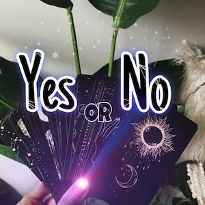 Può includere: Un set di carte da tarocchi nere con disegni celestiali bianchi, tra cui un sole, una luna e stelle. Le carte sono disposte a ventaglio in una mano, con il testo "Sì o No" sopra.