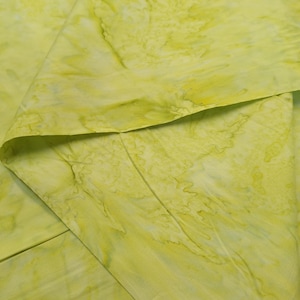 May include: A close-up of a light green fabric with a marbled pattern. The fabric is folded in half, showing the texture and color variations.