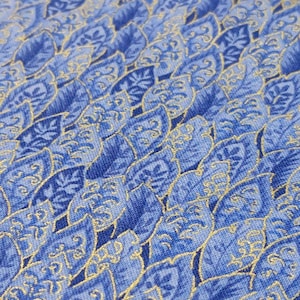 May include: Blue fabric with a gold leaf pattern. The fabric has a subtle sheen and a textured surface.