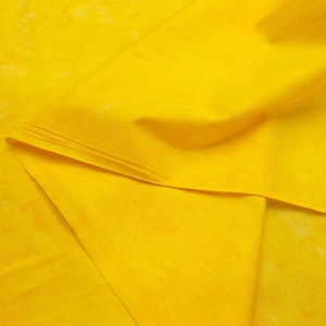 May include: A close-up of a yellow fabric with a subtle marbled pattern. The fabric is folded in half, creating a soft, draping effect.