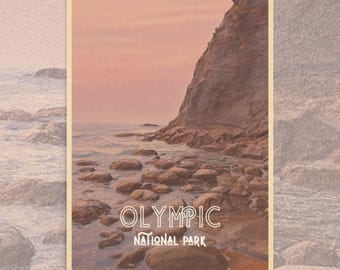 May include: A poster featuring a coastal landscape with the text "OLYMPIC NATIONAL PARK." The image shows a rocky shoreline, ocean, and a cliff under a pink and orange sky. The poster is held by two black binder clips.