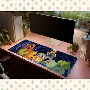 Peut inclure: Un tapis de bureau rectangulaire avec une impression graphique colorée représentant les personnages Salamèche, Pikachu, Carapuce, Sacha et Bulbizarre sur un fond de grotte bleu foncé, posé sur un bureau rose devant un écran d'ordinateur.
