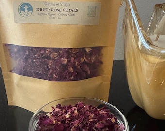 May include: A package of dried rose petals with the text "Garden of Vitality" and "Dried Rose Petals". A small glass bowl is filled with rose petals. A decorative glass object is in the background.