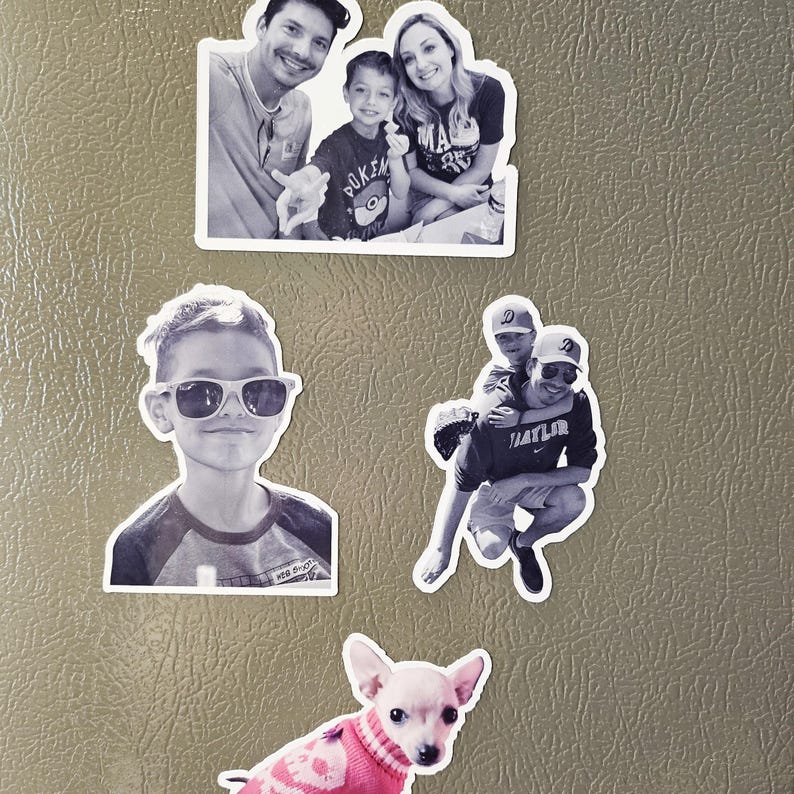 May include: Four black and white photos on a grey refrigerator. The top photo shows a family of three, a man, a woman, and a boy. The second photo shows a boy wearing sunglasses. The third photo shows two men, one carrying the other on his back. The bottom photo shows a small chihuahua wearing a pink sweater.