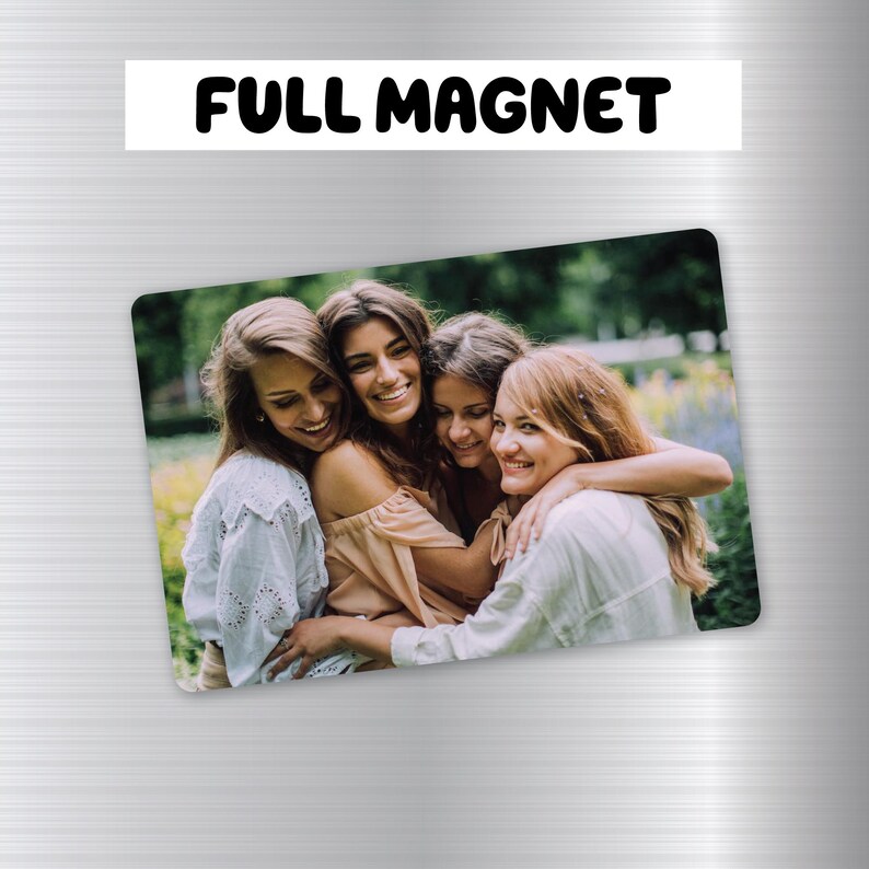 May include: Four women are smiling and hugging each other in a green grassy area. They are wearing casual summer clothing. The image is a photo magnet.