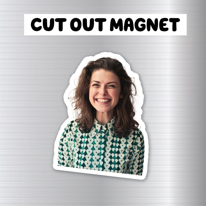 May include: A cut-out magnet featuring a smiling woman with long brown hair wearing a green and white patterned shirt.