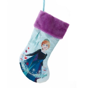 May include: A blue and purple Christmas stocking with a picture of Anna from Frozen. The stocking has a fluffy purple cuff and a white background with snowflakes.