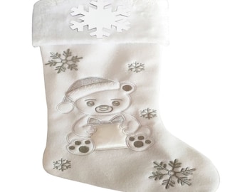 Op de afbeelding: Witte kerstsok met een pluche witte boord en een zilveren geborduurde teddybeer die een cadeau vasthoudt. De sok is versierd met zilveren sneeuwvlokken.