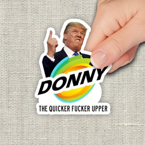 May include: A die-cut sticker featuring a photograph of Donald Trump in a dark suit and blue tie with his index finger raised. Below him is a colorful circular graphic with the text DONNY in bold black letters and THE QUICKER FUCKER UPPER.