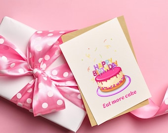 May include: A pink and white birthday cake with colorful candles that say "Happy Birthday" on top. The cake is on a purple plate with confetti around it. The card says "Eat more cake".
