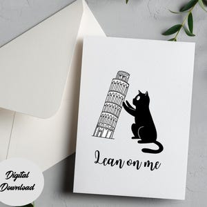 Op de afbeelding: Witte wenskaart met een zwarte illustratie van een kat die leunt op de scheve toren van Pisa. De tekst "Lean on me" staat eronder. Een witte envelop is zichtbaar op de achtergrond. De woorden "Digital Download" staan op een witte cirkel.