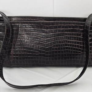 May include: A brown faux leather handbag with a crocodile-embossed pattern and a long shoulder strap.