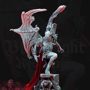 Puede incluir: Una figurita pintada de blanco de un vampiro con alas de murci&eacute;lago, de pie sobre una base de piedra con un pa&ntilde;o rojo drapeado sobre ella. El vampiro tiene dientes y garras afiladas y sostiene una espada en su mano derecha.