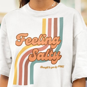 May include: White t-shirt with a retro-style graphic that says "Feeling Salty" with colourful stripes behind the text. The text "Brought to you by FOSS" is below the graphic.