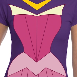 Puede incluir: Una camiseta morada con un diseño de corpiño rosa y rosa claro y un escote amarillo y blanco. El diseño se asemeja a un disfraz o vestido, con líneas y formas geométricas. La camiseta está hecha de un material suave.