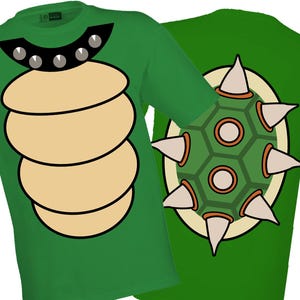 以下が含まれることがあります： 漫画のデザインの緑色のTシャツ。1つのシャツは、タン色の腹と、シルバーのスタッドが付いた黒い襟が特徴です。もう1つのシャツは、白いスパイクが付いた緑とタン色のシェルを示しています。アパレル。