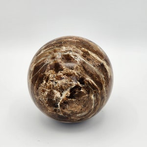 May include: A brown and white marble sphere with a swirling pattern.