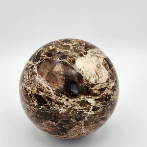 May include: A smooth, round, brown and white marble sphere with a swirling pattern.