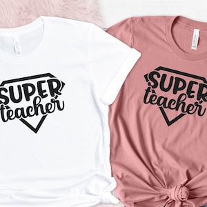 May include: Two t-shirts with the text "SUPER teacher" in a diamond shape. One shirt is white and the other is pink.