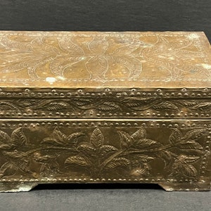 May include: A vintage brass box with an intricate floral design. The box has a hinged lid and is decorated with raised floral motifs.