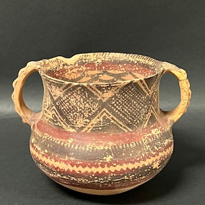 May include: A brown ceramic pot with two handles and geometric designs in black and red paint.