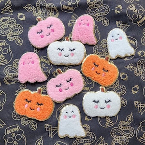 May include: Nine felt Halloween-themed patches.  There are three pink ghosts, three orange pumpkins, and three white pumpkins.  Each patch has a smiling face with closed eyes.