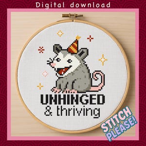 May include: A cross-stitch design in a wooden hoop features a gray opossum wearing a party hat. The text "UNHINGED & thriving" is below the opossum. The words "Stitch Please!" are in a speech bubble. The words "Digital download" are at the top.
