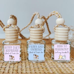 May include: Four car air fresheners with different scents and designs. The scents are "Calm the Claws", "Ruff Day Refresh", "Paws and Unwind", and "Hiss to Harmony". Each air freshener has a small cartoon animal on the label.