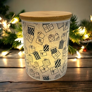 May include: A white ceramic jar with a bamboo lid, featuring a repeating pattern of black and white gift boxes. The jar is filled with a white substance.
