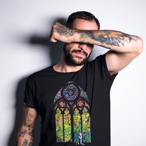 Könnte beinhalten: Ein schwarzes T-Shirt mit einem bunten Buntglasfenster-Design. Das Fenster besteht aus kleinen Quadraten in verschiedenen Farben und das Design erinnert an ein Kirchenfenster.