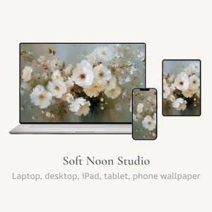 May include: A laptop, phone, and tablet display a floral wallpaper design. The wallpaper features white flowers with yellow centers and green leaves against a muted background. The text "Soft Noon Studio" and "Laptop, desktop, iPad, tablet, phone wallpaper" are below the devices.
