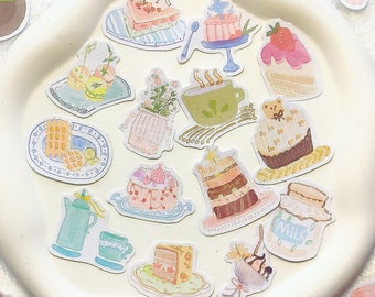 Könnte beinhalten: Eine Sammlung bunter Aufkleber mit verschiedenen Designs, darunter Kuchen, Gebäck, Teetassen und andere skurrile Illustrationen. Die Aufkleber sind auf einem weißen Teller und einem weißen Hintergrund angeordnet.