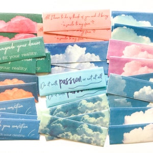 May include: A collection of colourful paper strips with inspirational quotes and a sky background. The quotes include "Don't downgrade your dream just to fit your reality." and "Do it with passion or not at all."