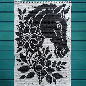 May include: A rectangular crochet wall hanging featuring a black and white tapestry design. The pattern displays the profile of a horse head positioned above detailed floral and leaf motifs, all rendered in a contrasting two-tone color scheme.