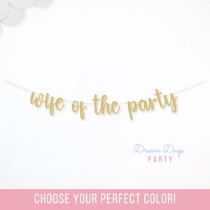 May include: A gold glitter banner that reads "wife of the party" is strung across the center of the image. The words are in a cursive font. White balloons are in the upper left corner. The text "Dream Days Party" is in the lower right corner.