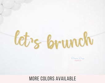 May include: Gold glitter "Let's Brunch" banner strung on a white string, perfect for a brunch party. White balloons are visible in the upper left corner. The words "Dream Days Party" are in the lower right corner, with the text "MORE COLORS AVAILABLE" below.