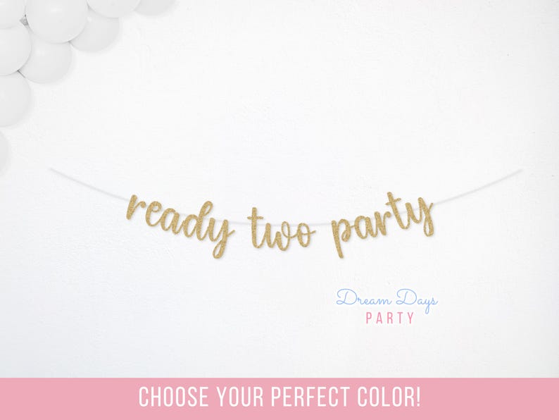 May include: A gold glitter banner that reads "ready two party" on a white string. The banner is against a white background with white balloons in the upper left corner. The text "Dream Days Party" is below the banner.