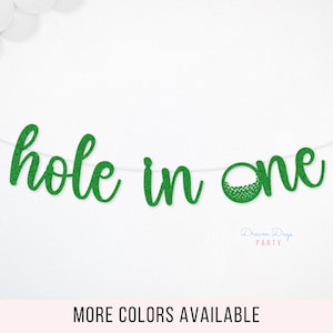 May include: A green glitter "hole in one" banner, perfect for a golf-themed party. The banner is strung on a white string and features a golf ball graphic. Additional colors are available.